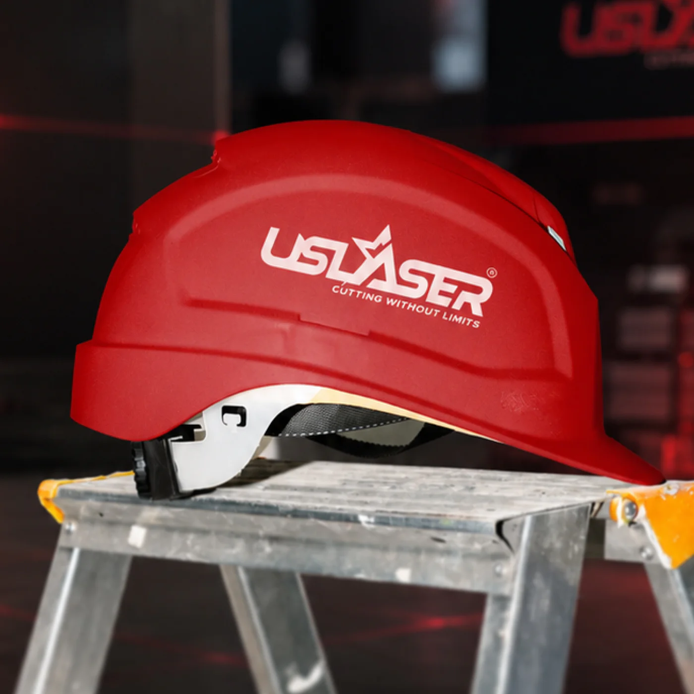 Red US Laser hard hat displayed on a metal workbench