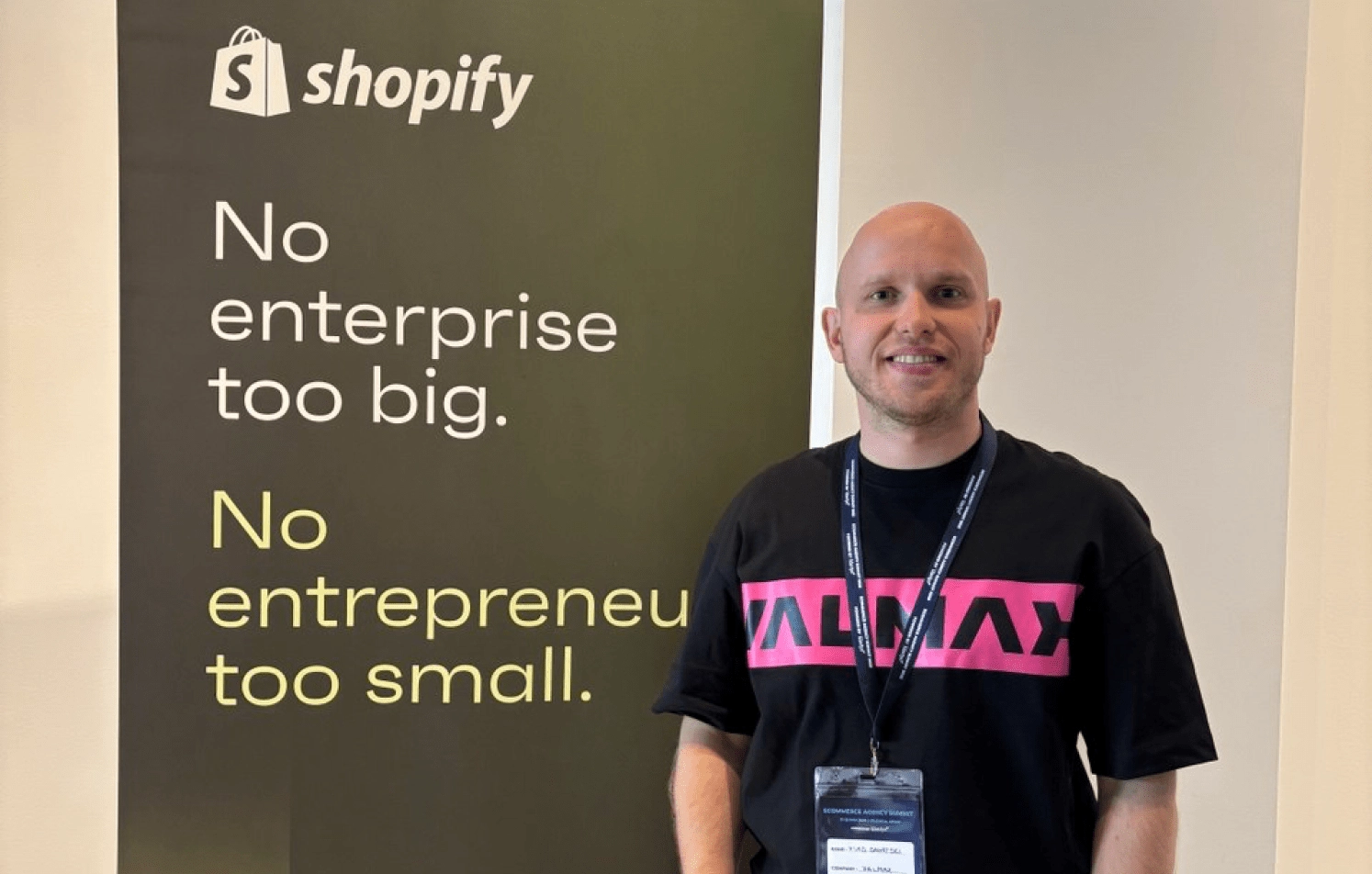 Man at Shopify Event with Valmax T-Shirt Man next to Shopify banner in Valmax t-shirt.