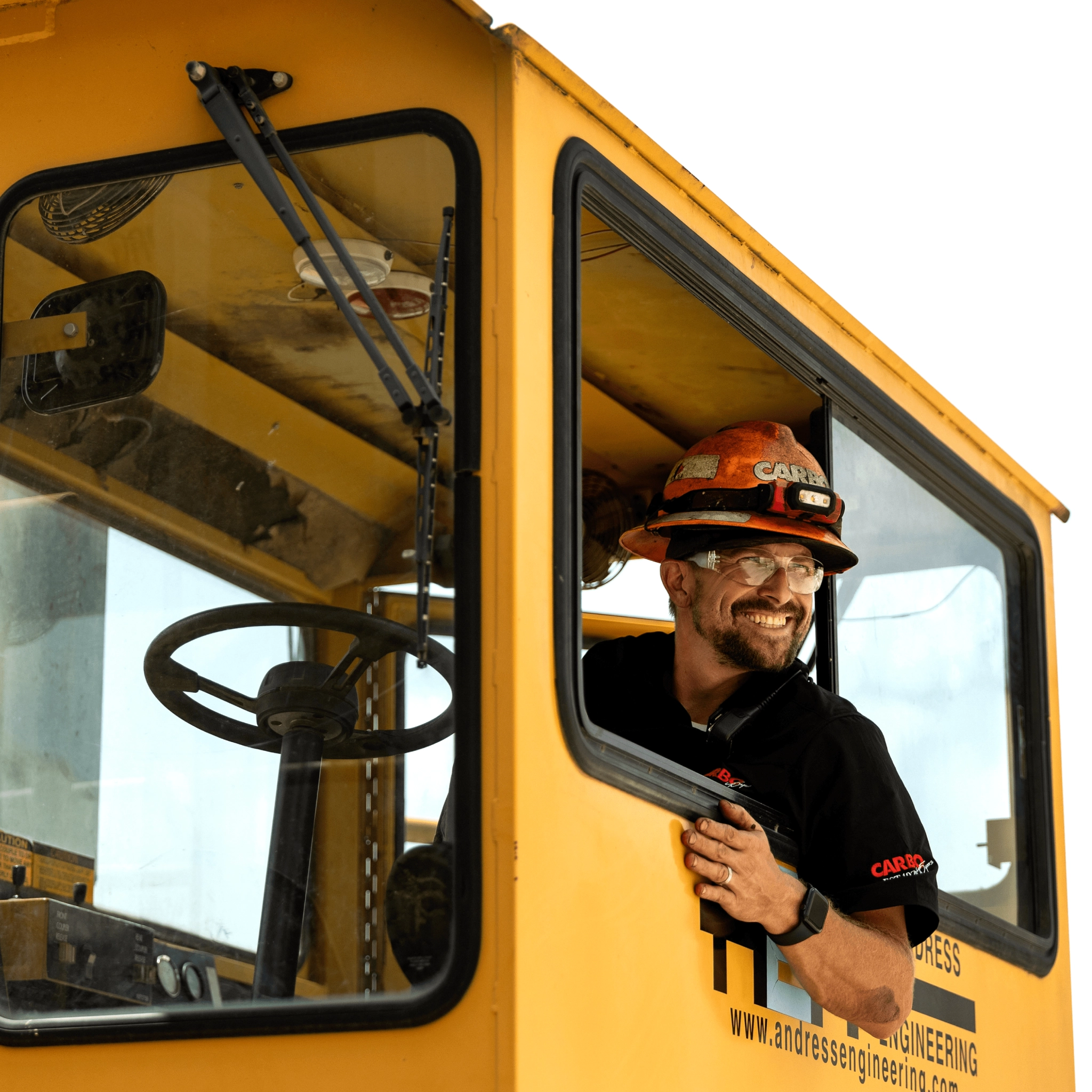 Smiling worker in construction cab Worker in helmet driving machine